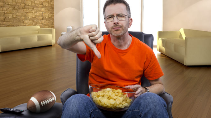 man watching football on TV with potato chip snacks