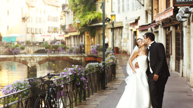 Happy married couple bride and groom kissing & hugging in old french street