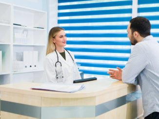 Man talking to female receptionist at hospital.