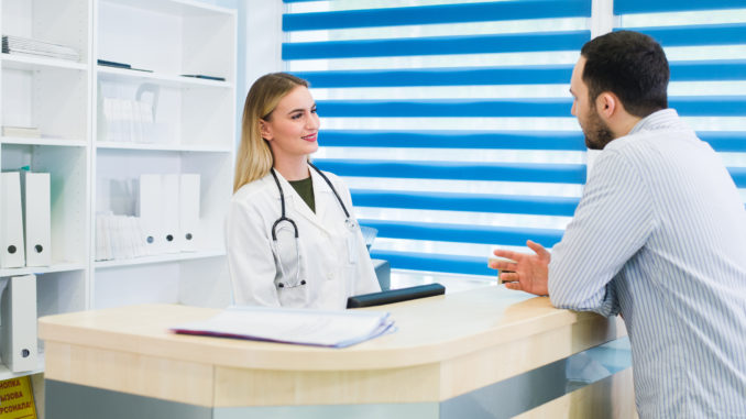 Man talking to female receptionist at hospital.