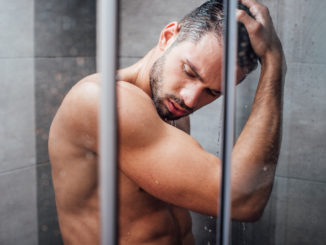 selective focus of handsome man with eyes closed taking shower in bathroom