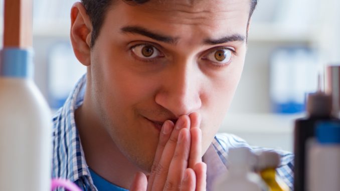 Sick ill man looking for medicines at farmacy shelf