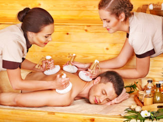 Man getting herbal ball massage treatments in spa.