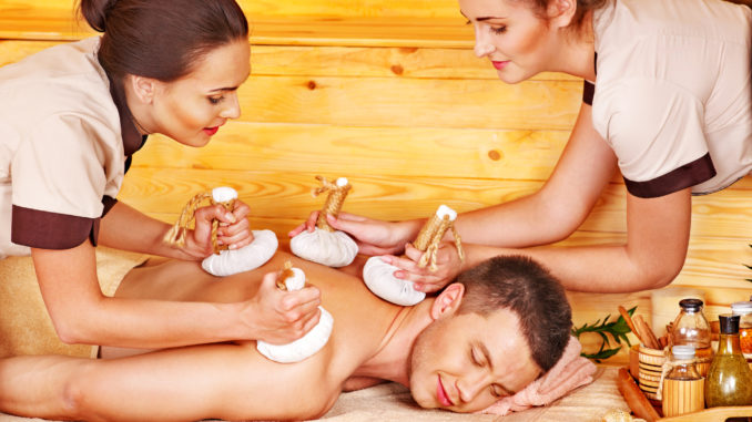Man getting herbal ball massage treatments in spa.