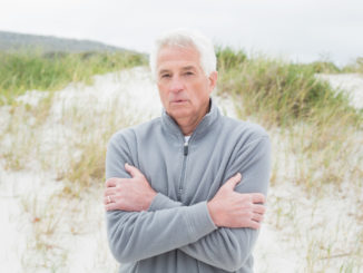 Portrait of a casual senior man feeling cold at the beach