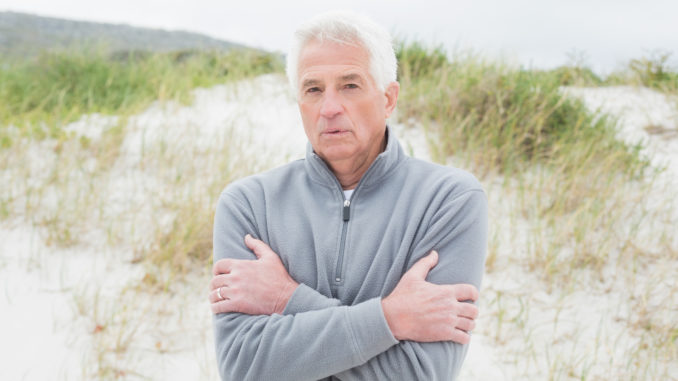 Portrait of a casual senior man feeling cold at the beach