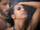 Tanned, dark-haired girl in a bathing suit and a men with a beard relaxing shower. Tropics. Horizontal photo
