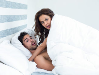 Portrait of surprised young couple enjoying on bed in room