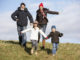 Family Running In The Park Wearing Winter Clothes