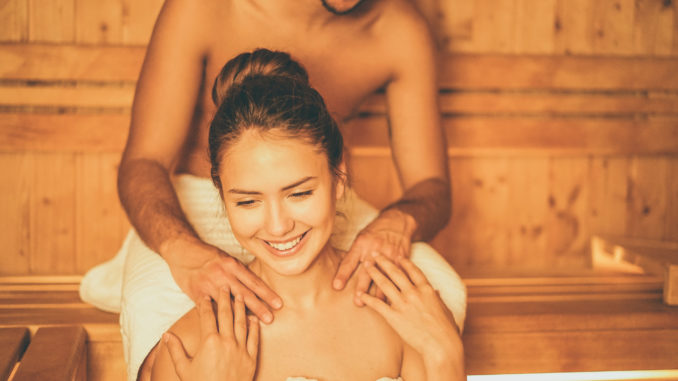 Young happy couple relaxing inside a sauna at spa resort hotel luxury - Romantic lovers having a bodycare day in steam bath man making a massage for his girlfriend - Relax, love, lifestyle concept