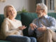 Happy carefree excited elderly family couple laughing, joking, talking, sharing good news, enjoying common weekend time in cozy living room, old people funny activities concept.