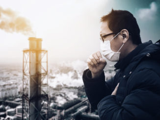 Man wearing mask against smog and air pollution factory background.