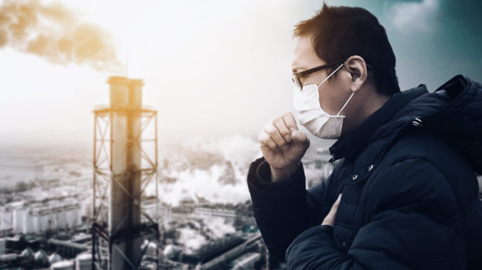 Man wearing mask against smog and air pollution factory background.