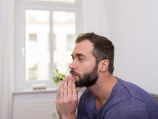 Worried bearded man sitting thinking with his clasped hands to his chin staring off into space in contemplation