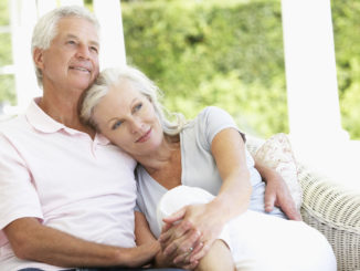 Senior Couple Relaxing On Seat Outside House