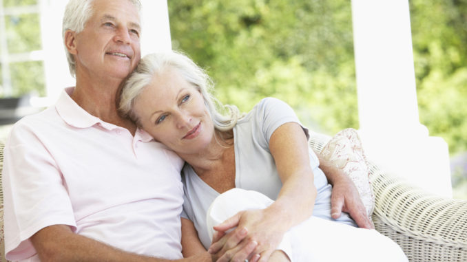 Senior Couple Relaxing On Seat Outside House