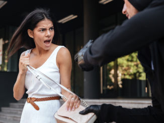 Angry young women shouting and protecting from men thief with gun on the street