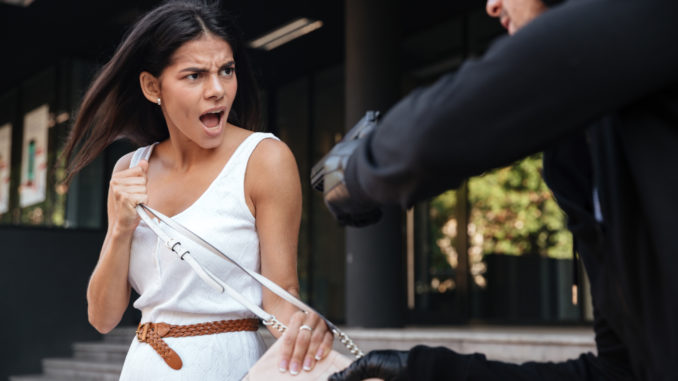 Angry young women shouting and protecting from men thief with gun on the street