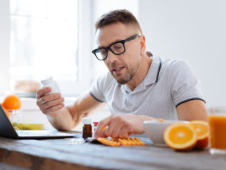 Biohack your life. Handsome progressive doubtful man deciding about biohacking supplements while sitting and improving his health