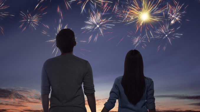 Young asian couple watching spectacular fireworks on the sky