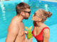 Young couple with refreshing cocktails near swimming pool at resort