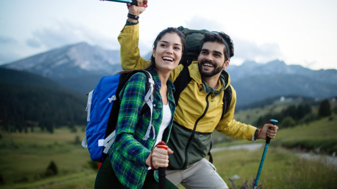 Backpackers happy beautiful couple hiking with sticks