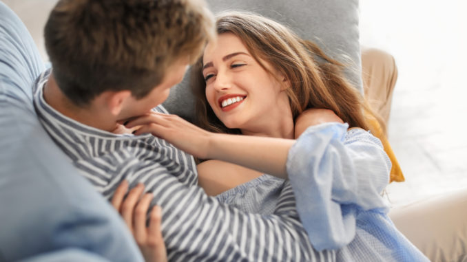 Happy young couple resting on sofa at home