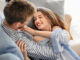 Happy young couple resting on sofa at home