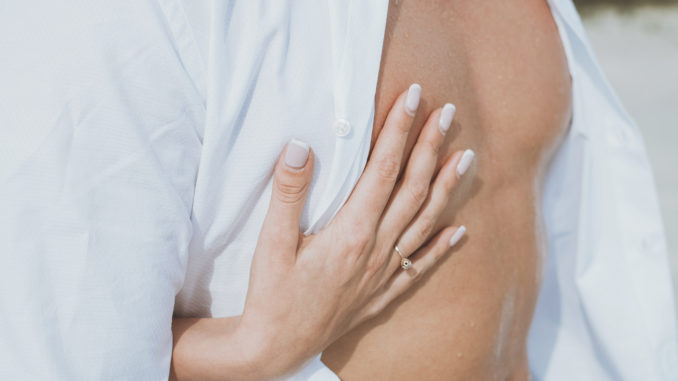 muscular naked man and female hands unbuckle his jeans