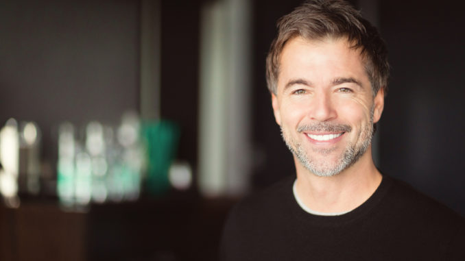 A handsome smiling middle-aged man with a short grey beard and brown hair.