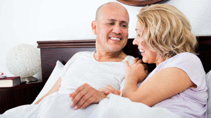 Cheerful mature loving couple lounging in bed after awaking cuddling