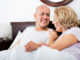 Cheerful mature loving couple lounging in bed after awaking cuddling