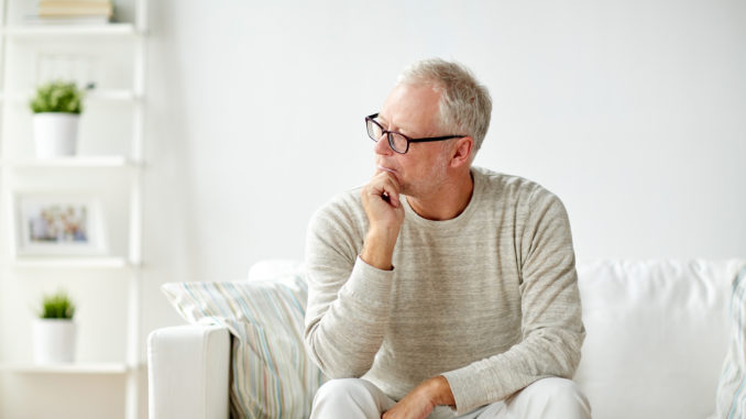 Old age, problem and people concept - senior man in glasses thinking and sitting on sofa at home