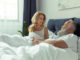 Beautiful happy mature couple lying together in bed and smiling each other