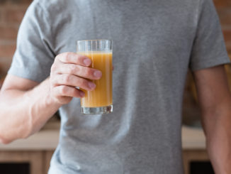 unrecognizable man holding a glass with a drink.