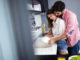 Young happy couple is washing dishes and hugging smiling