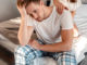 Young couple in the bed. Close-up of unhappy men in pajamas is sitting on the edge of bed, problem in the bedroom