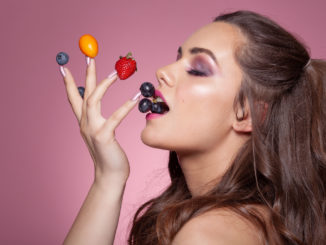 Young woman eating fruits from her fingers.