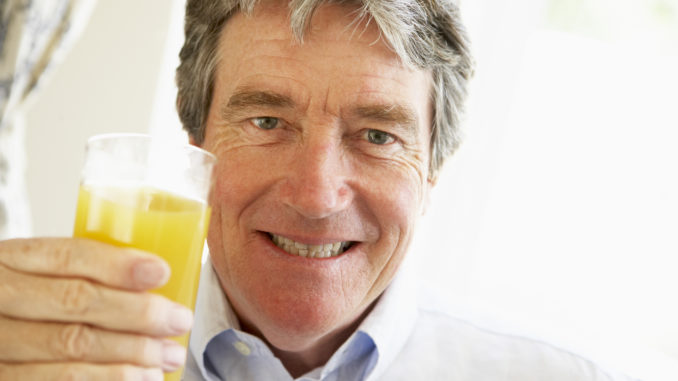 Senior Man Smiling At Camera And Drinking Orange Juice