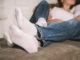 Young man and woman, couple in love lying on bed embracing legs in jeans, casual style, happy together, romantic mood, barefoot