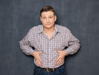 Studio half-length portrait of dissatisfied man having overweight caused by metabolic disorder or overeating, putting hands on his fat stomach, looking disappointed and upset, over gray background