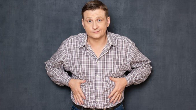 Studio half-length portrait of dissatisfied man having overweight caused by metabolic disorder or overeating, putting hands on his fat stomach, looking disappointed and upset, over gray background