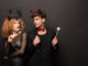 Beautiful couple posing in halloween costumes with sweet lollipops on black