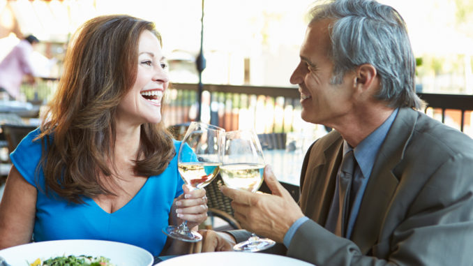 Mature Couple Enjoying Meal At Outdoor Restaurant smiling at each other