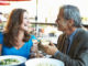 Mature Couple Enjoying Meal At Outdoor Restaurant smiling at each other