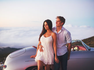Romantic Young Attractive Couple Watching the Sunset with Classic Vintage Sports Car