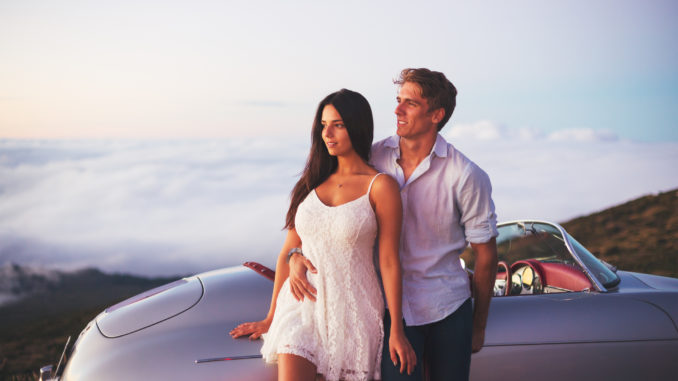 Romantic Young Attractive Couple Watching the Sunset with Classic Vintage Sports Car