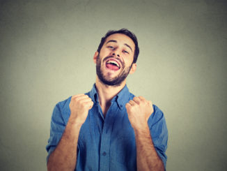 Closeup portrait happy successful student, business man winning, fists pumped celebrating success grey wall background.