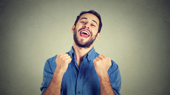 Closeup portrait happy successful student, business man winning, fists pumped celebrating success grey wall background.