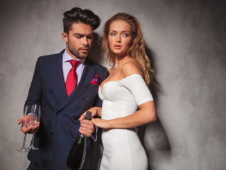 Side view of a hot fashion couple with champagne and glasses ready to celebrate